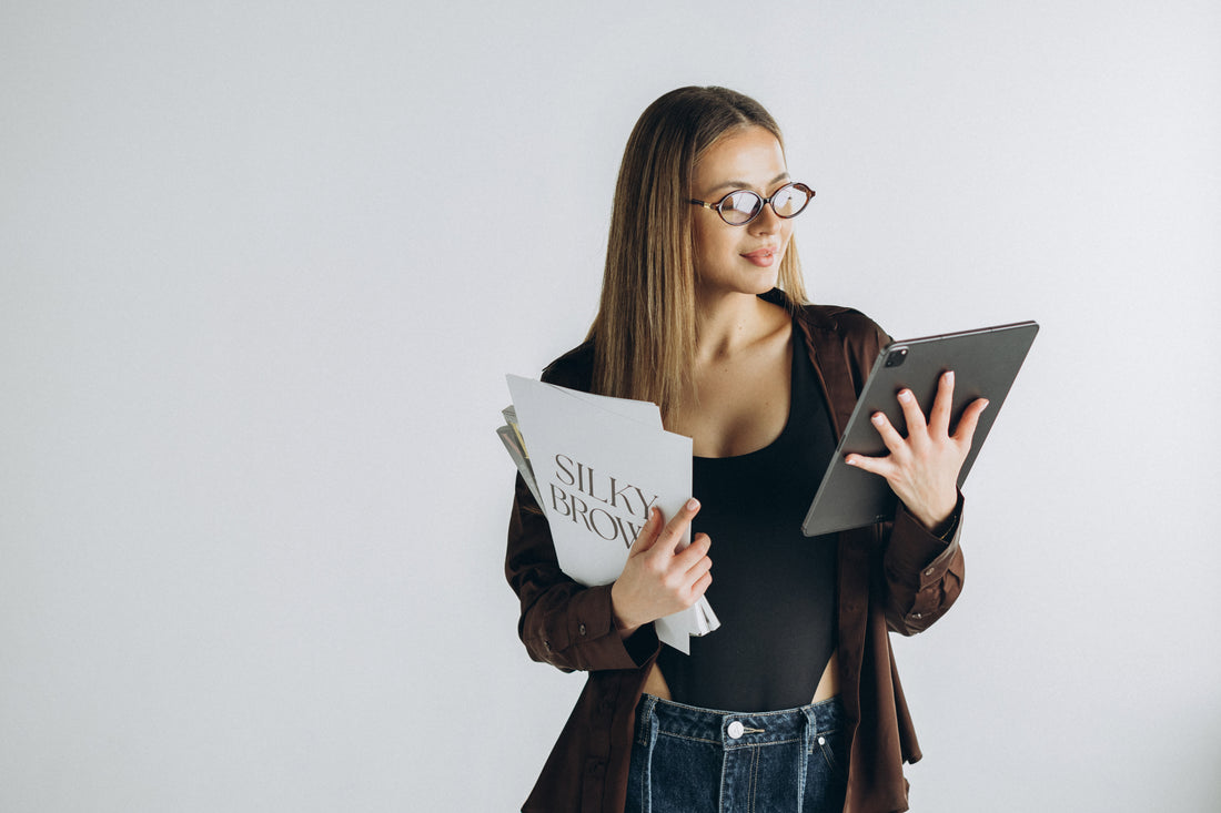 Woman holding a tablet and a book with a plain background